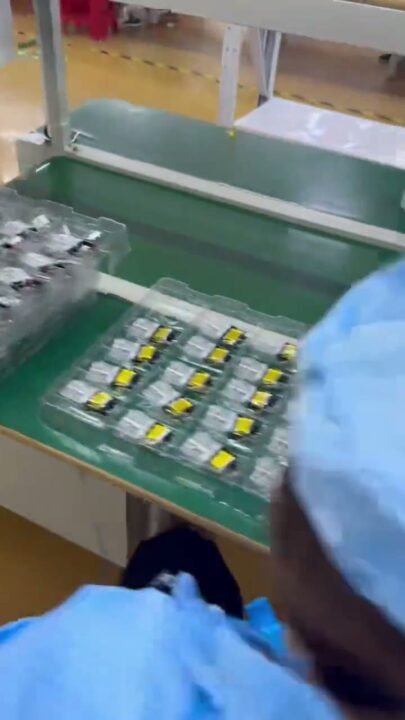 Worker running electrical testing on empty vape hardware units before packing