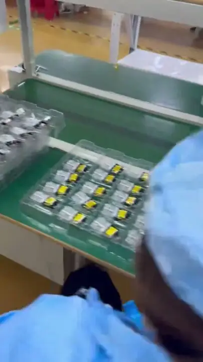 Worker running electrical testing on empty vape hardware units before packing
